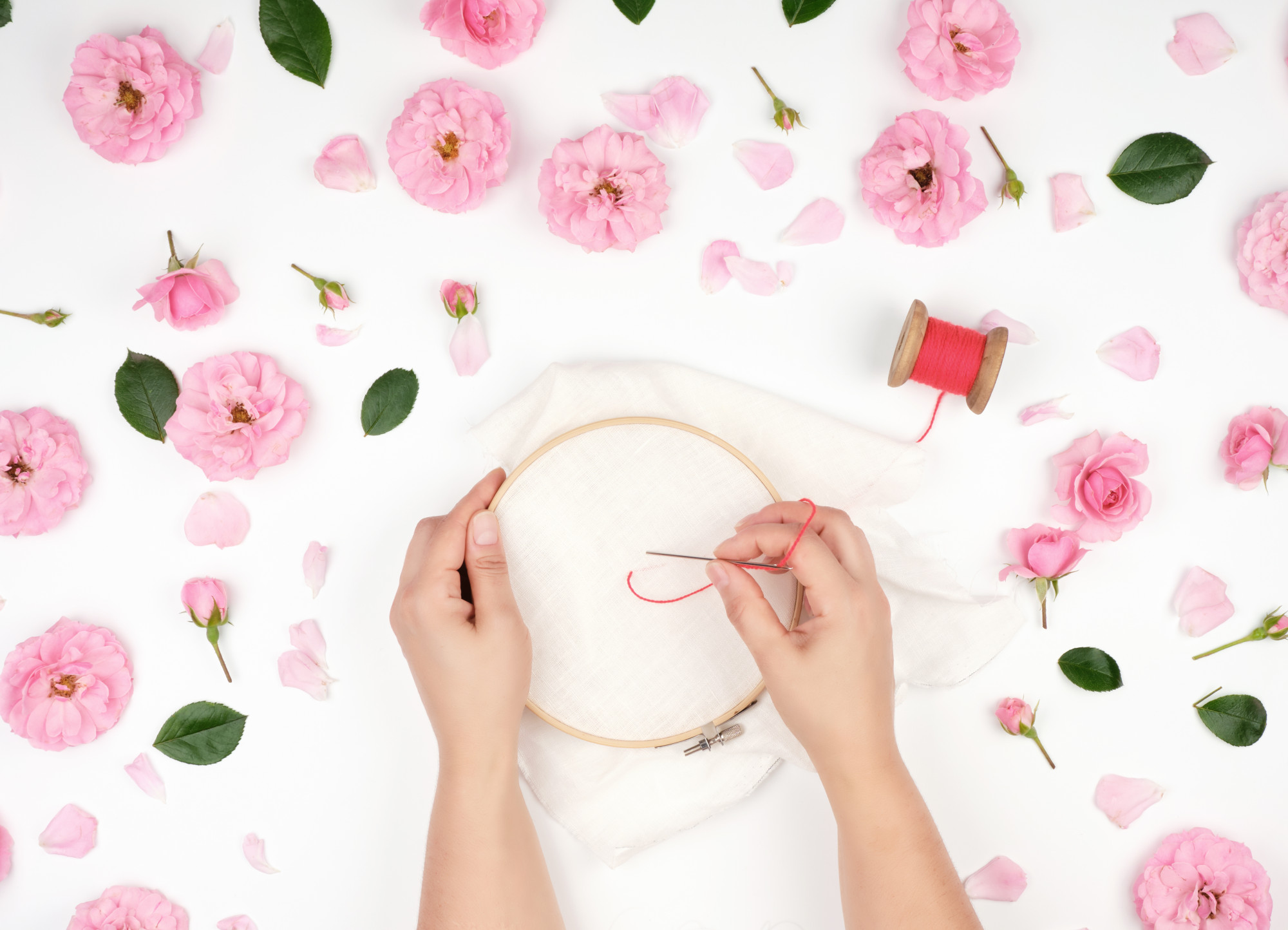 Hands stitching floral pattern on fabric